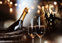 Background for new year congratulations with champagne and a clock (Bild: © gudrun - Fotolia.com)