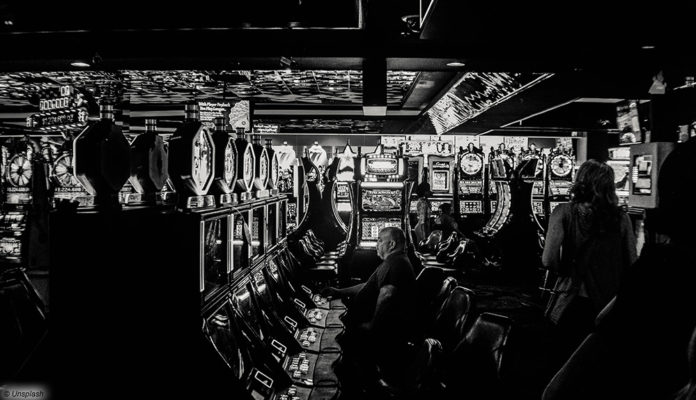 Mehrere Menschen zocken an Spielautomaten in einem Casino