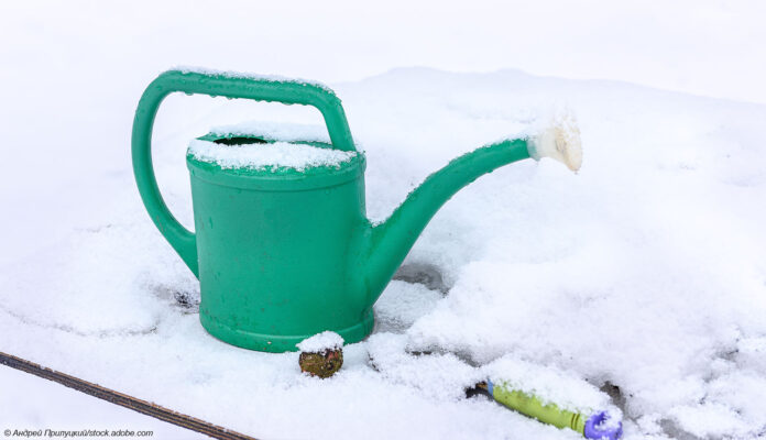 Gießkanne und Schnee im Garten