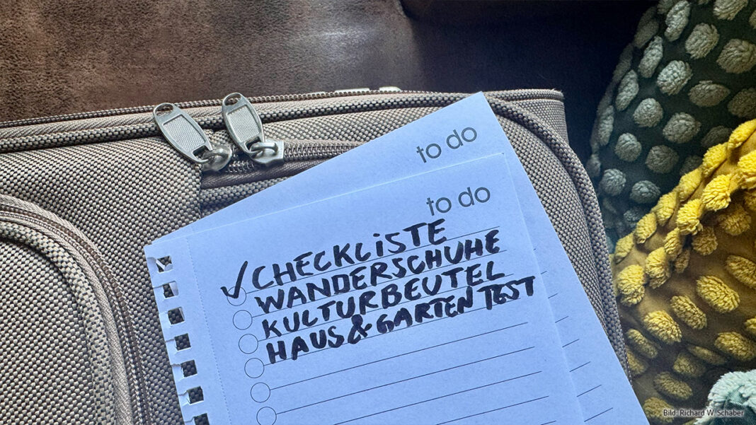 Checkliste zum Packen liegt auf auf einem Koffer: Handgeschrieben und bereit zum Abhaken, 