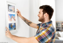 Mann befestigt Bild an Wand