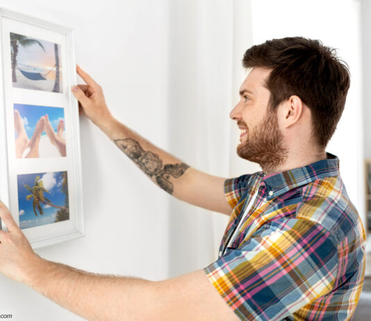 Mann befestigt Bild an Wand