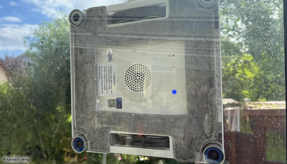 Der Ecovacs haftet an der Scheibe und die Fortbewegung entlang der Glasfläche erfolgt durch Gummiriemen
